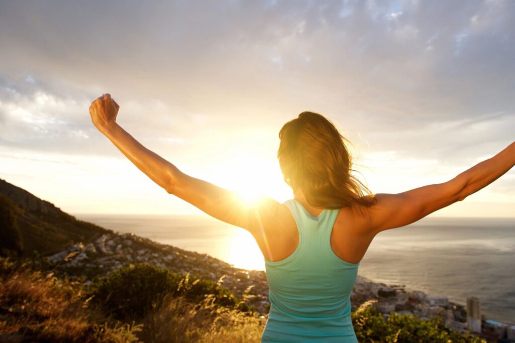 happy woman with arms raised enjoying freedom from pain