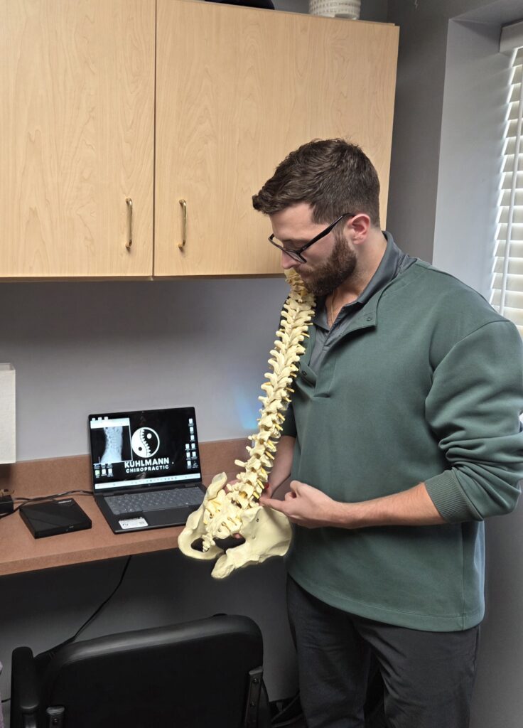 Dr. Kuhlmann holding a model spine